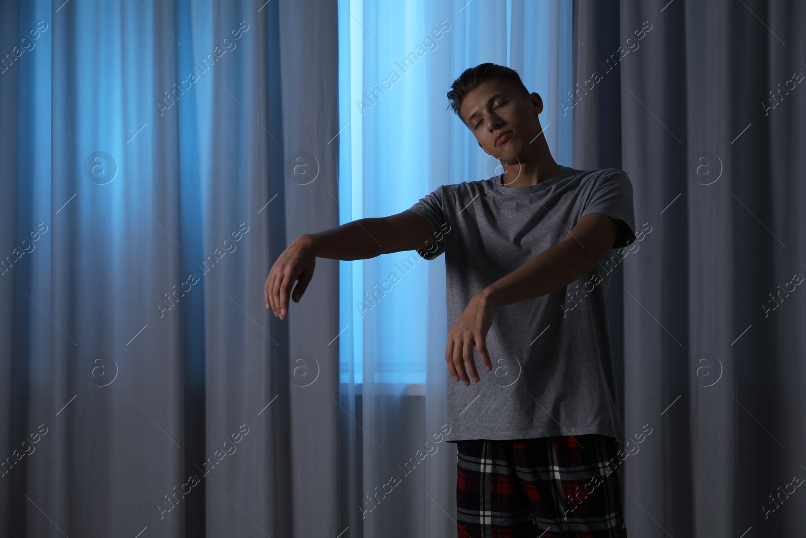 Photo of Young man suffering from sleepwalking at home, space for text