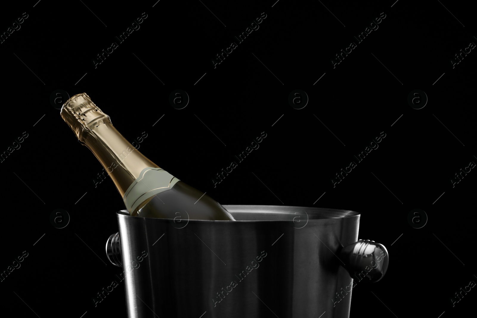 Photo of Bottle of champagne in bucket on black background