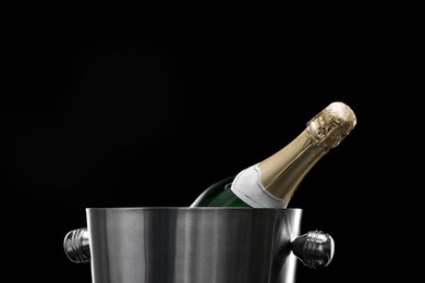 Photo of Bottle of champagne in bucket on black background