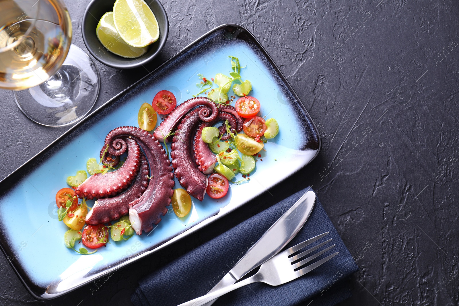 Photo of Tasty boiled octopus tentacles and salad served on grey textured table, flat lay