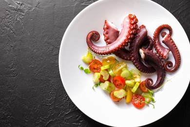 Photo of Plate with tasty boiled octopus tentacles and salad on grey textured table, top view. Space for text