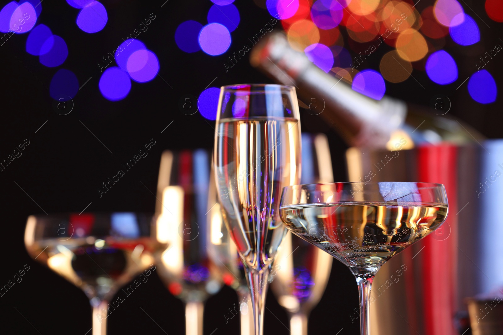 Photo of Champagne in glasses against black background with blurred lights, closeup