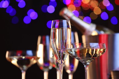 Photo of Champagne in glasses against black background with blurred lights, closeup