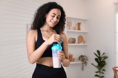 Beautiful woman with protein shake at home