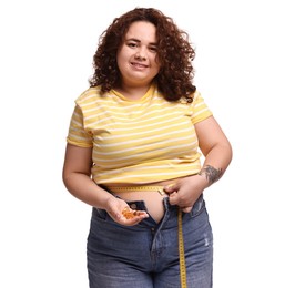 Photo of Happy plus size woman measuring waist with tape and holding pile of weight loss supplements on white background