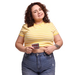 Photo of Happy plus size woman with blister of weight loss supplements on white background