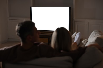 Photo of Couple watching TV on sofa at home in evening