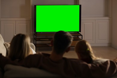 Photo of Family watching TV on sofa at home, back view