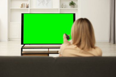 Photo of Woman watching TV on sofa at home, back view