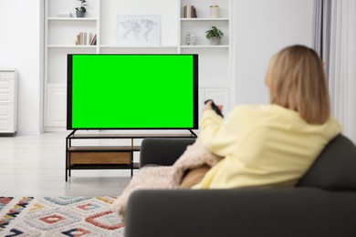 Photo of Woman watching TV on sofa at home, back view