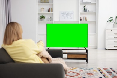 Woman watching TV on sofa at home, back view