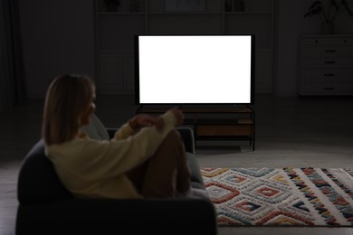 Photo of Woman watching TV on sofa at home in evening