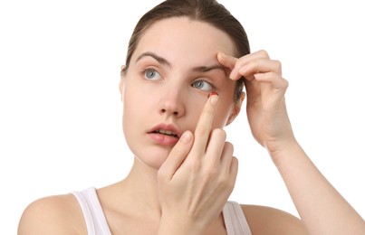 Photo of Young woman putting in red color contact lens on white background