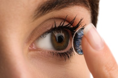 Photo of Woman putting in blue color contact lens on white background, closeup