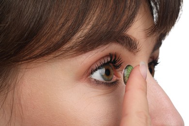 Photo of Young woman putting in green color contact lens on white background, closeup