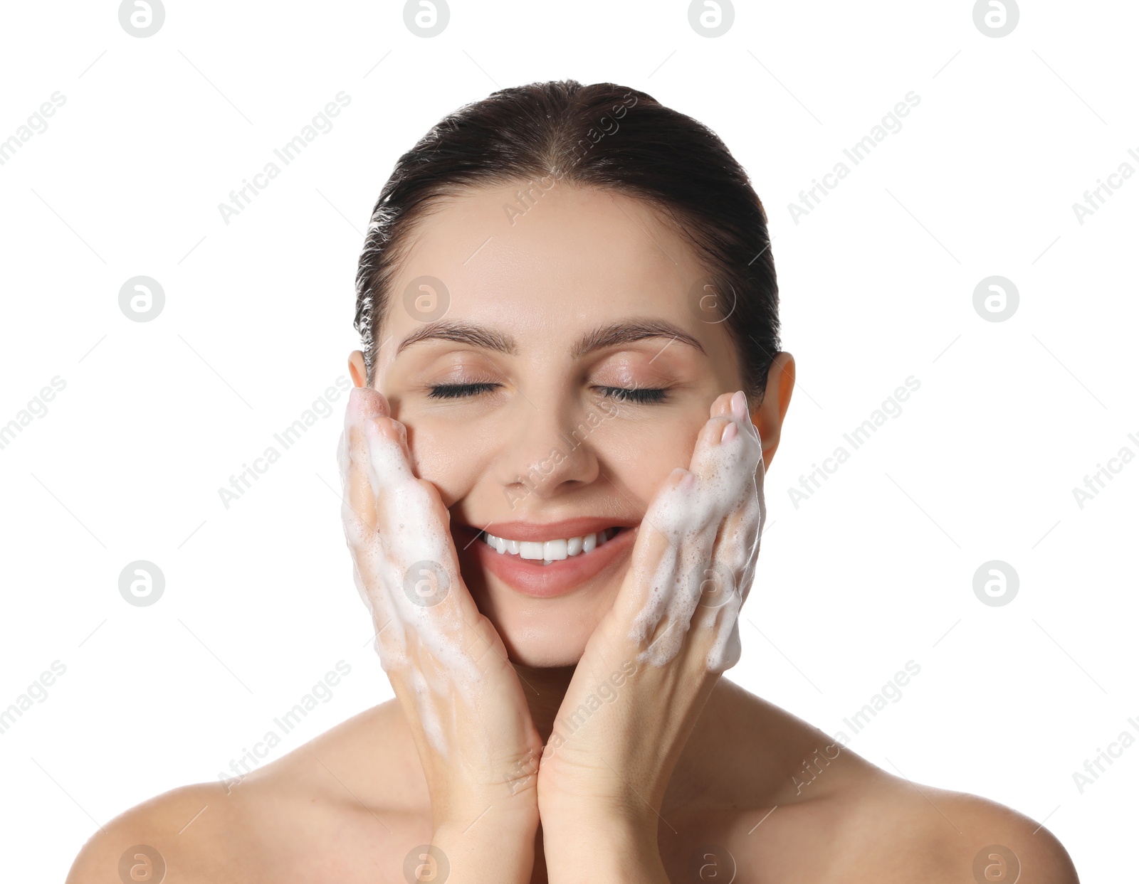 Photo of Smiling woman washing her face with cleansing foam on white background