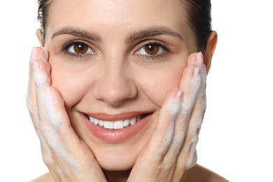 Photo of Smiling woman washing her face with cleansing foam on white background