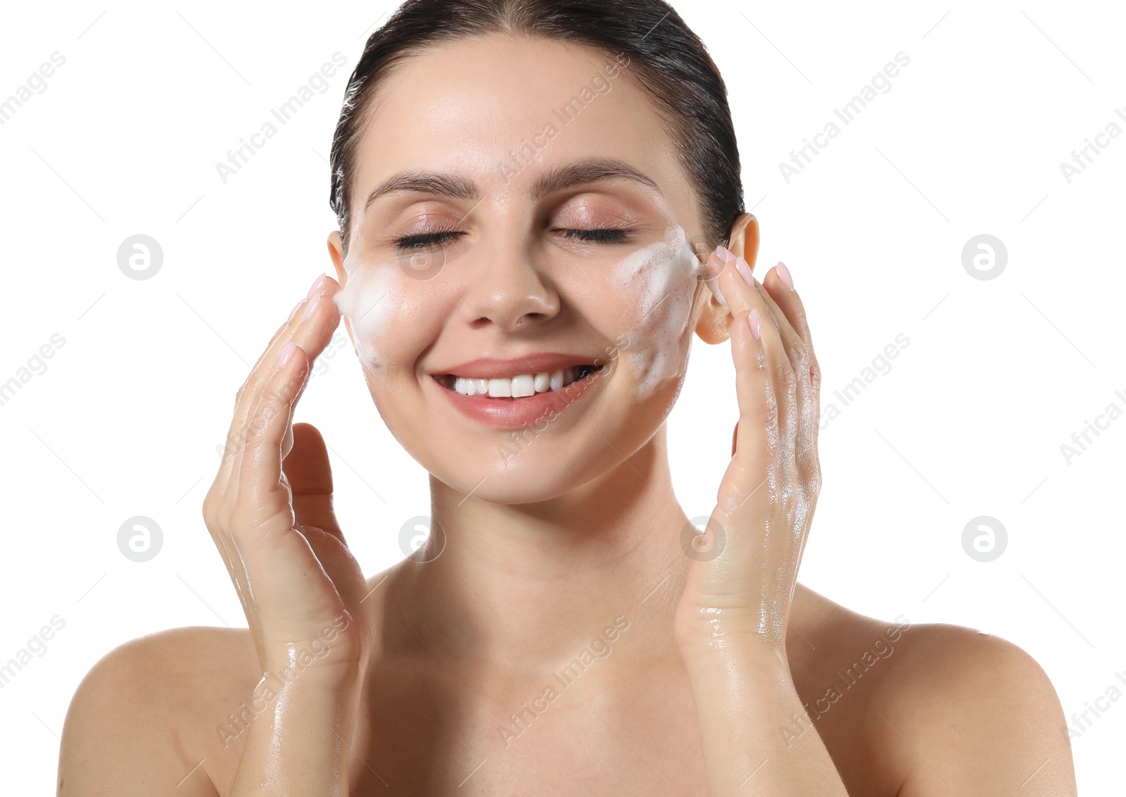 Photo of Smiling woman washing her face with cleansing foam on white background