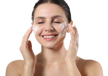 Smiling woman washing her face with cleansing foam on white background