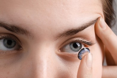 Photo of Woman putting in blue color contact lens, closeup