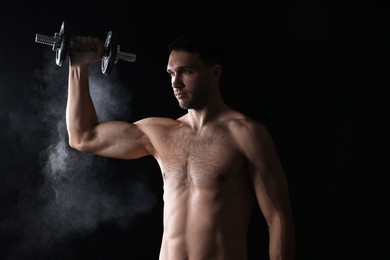 Man with talcum powder on hand training with barbell against black background