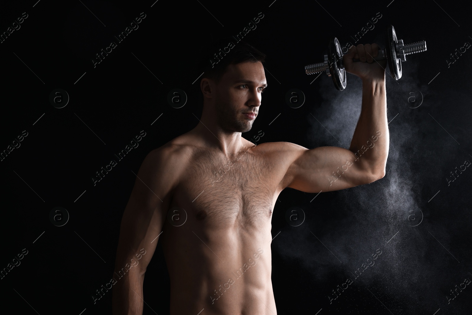 Photo of Man with talcum powder on hand training with barbell against black background