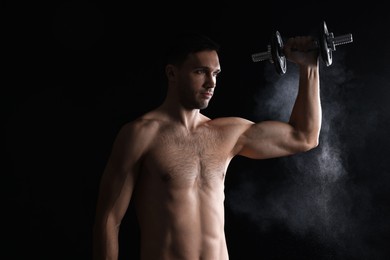 Man with talcum powder on hand training with barbell against black background