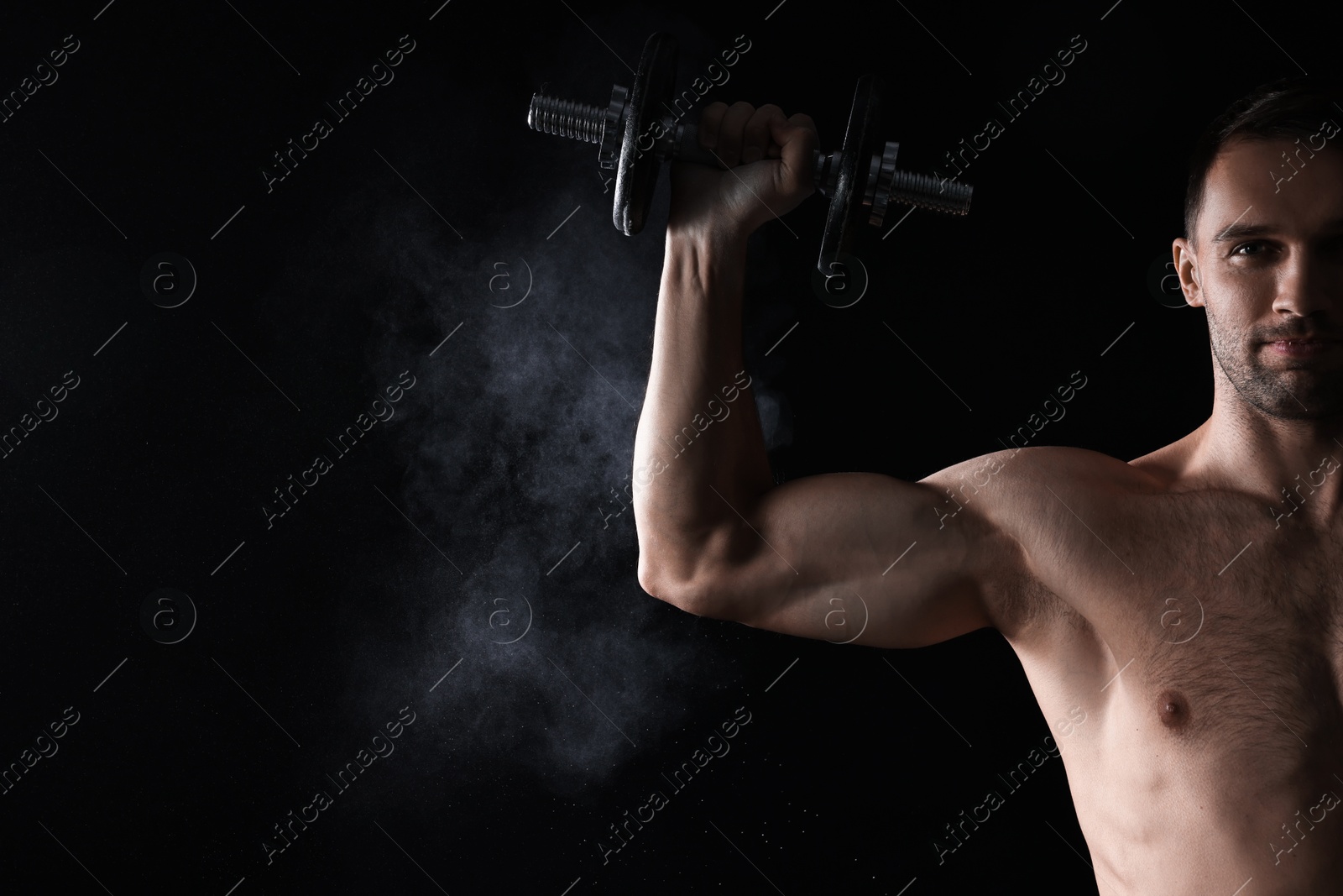 Photo of Man with talcum powder on hand training with barbell against black background. Space for text