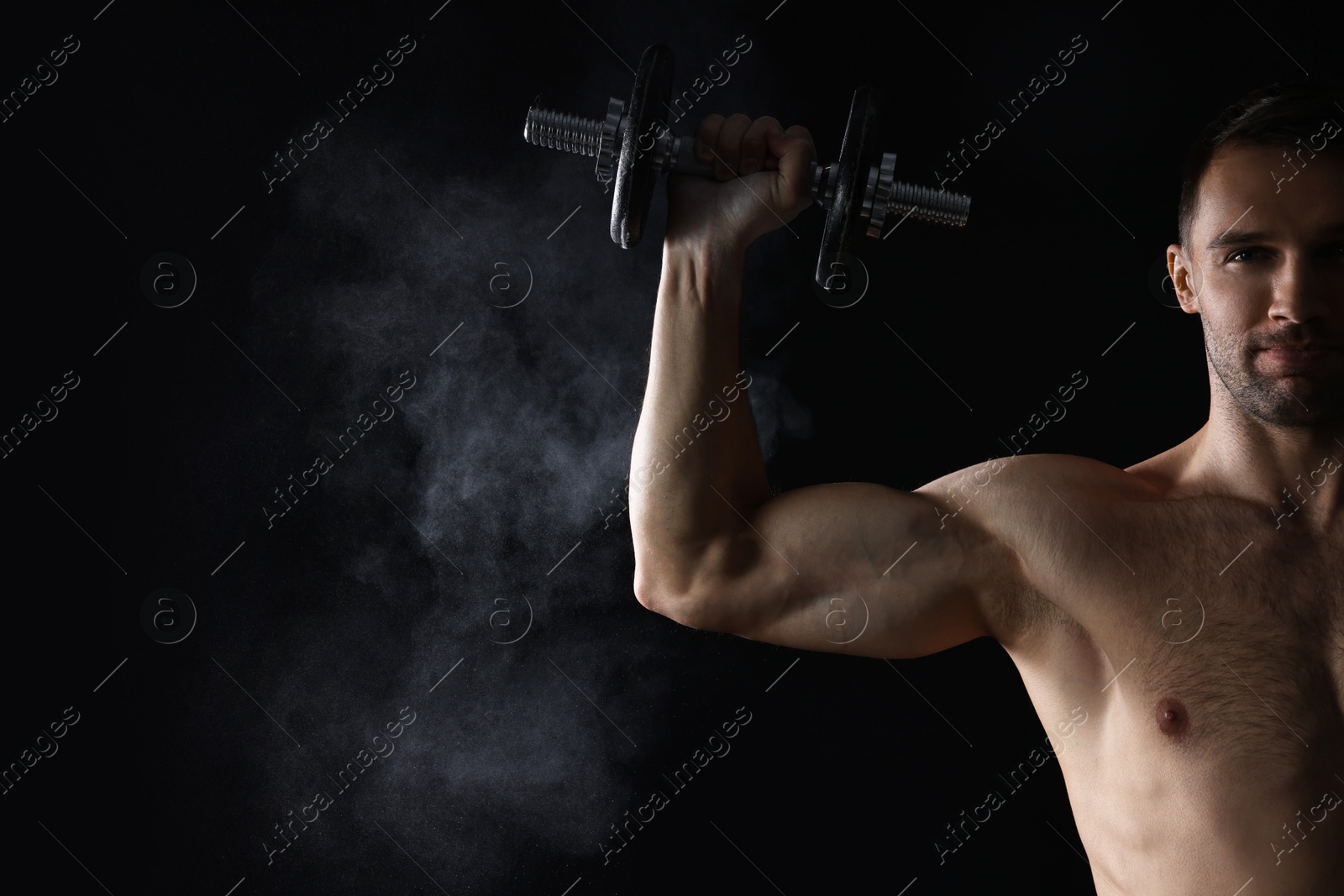 Photo of Man with talcum powder on hand training with barbell against black background. Space for text