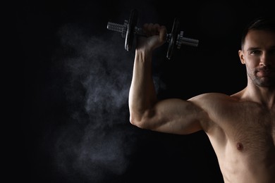 Man with talcum powder on hand training with barbell against black background. Space for text