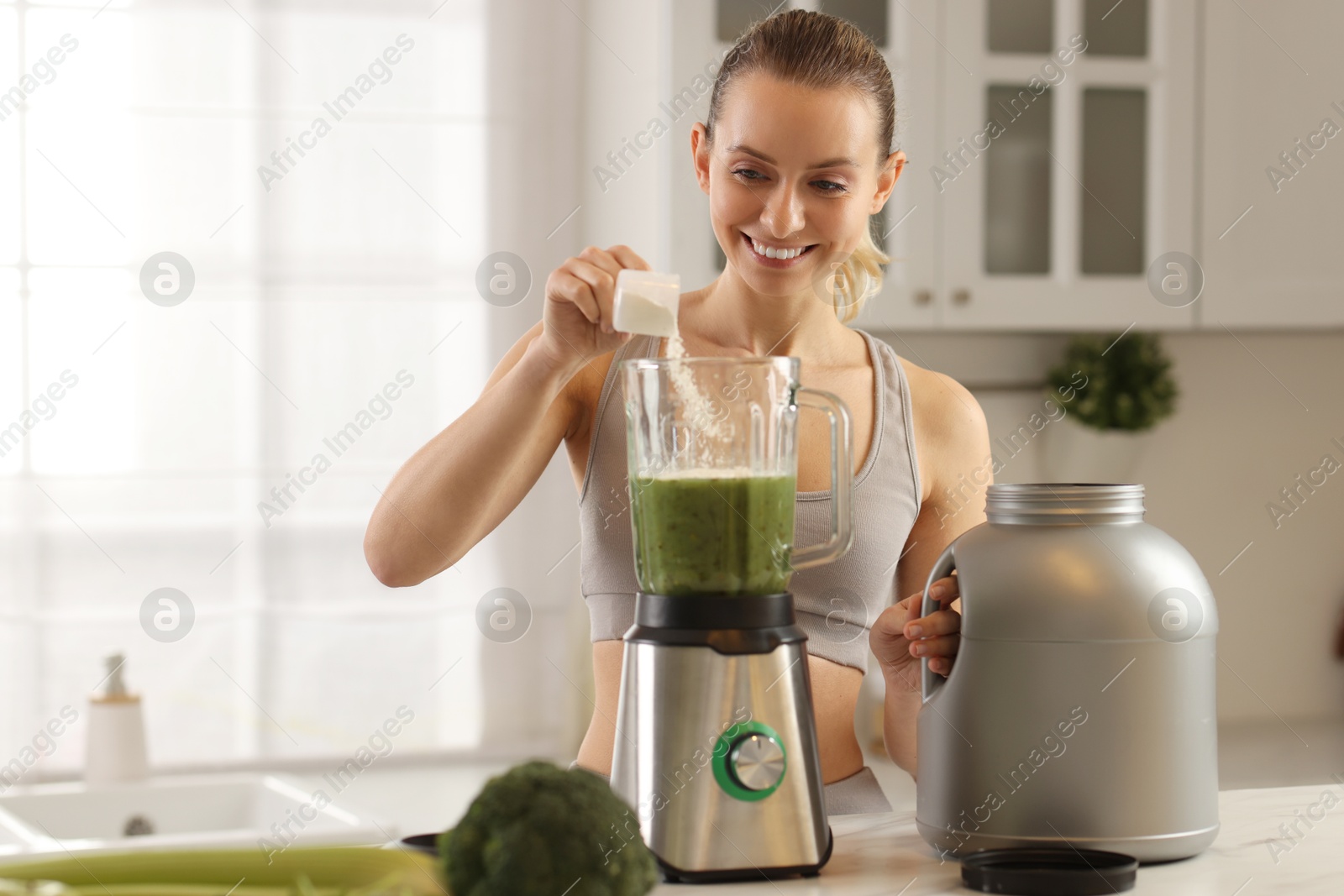 Photo of Weight loss. Happy woman making protein shake at table in kitchen