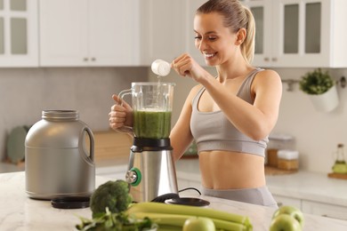 Photo of Weight loss. Happy woman making protein shake at table in kitchen