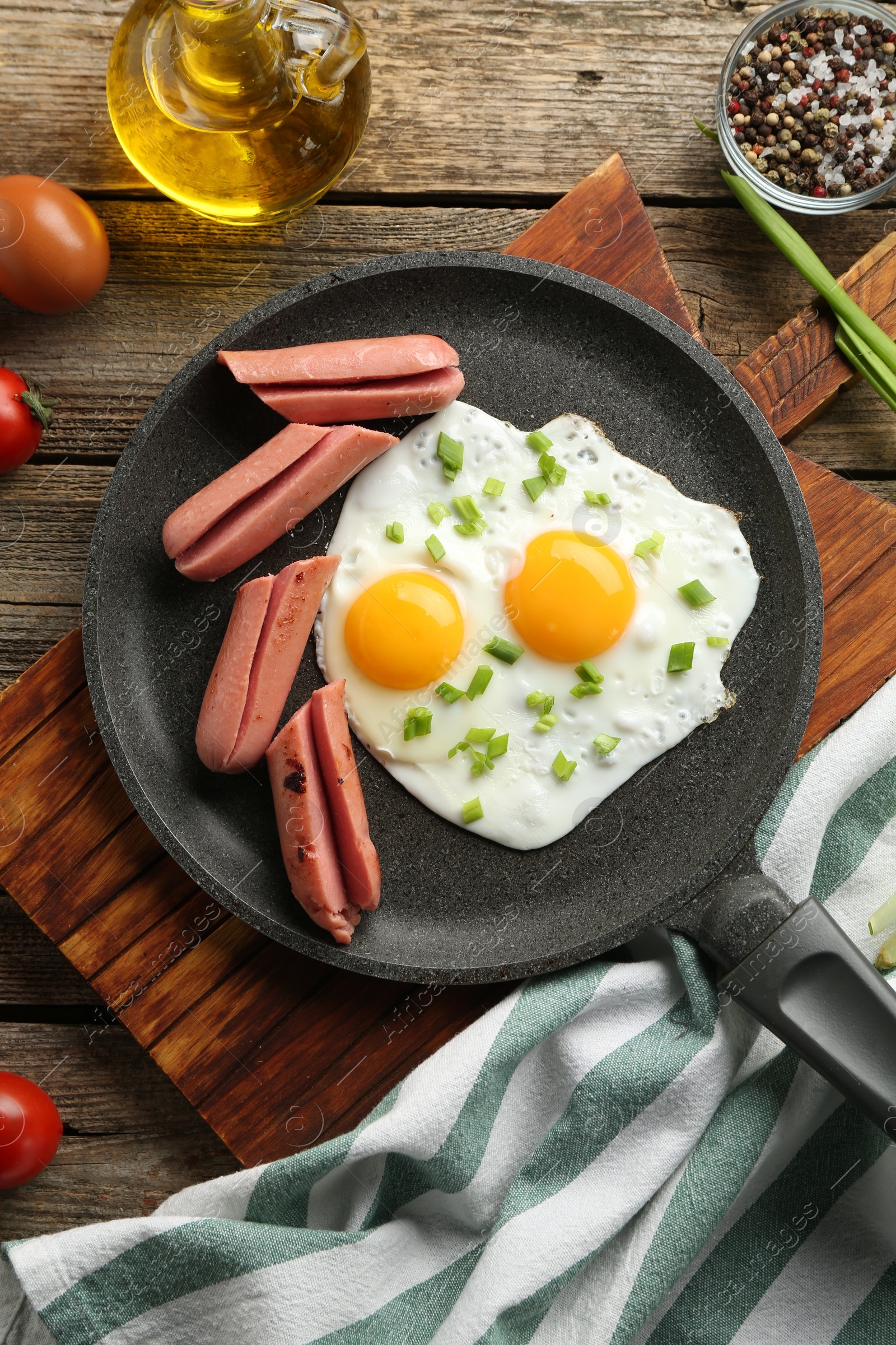 Photo of Tasty fried eggs with cut sausages served on wooden table, flat lay