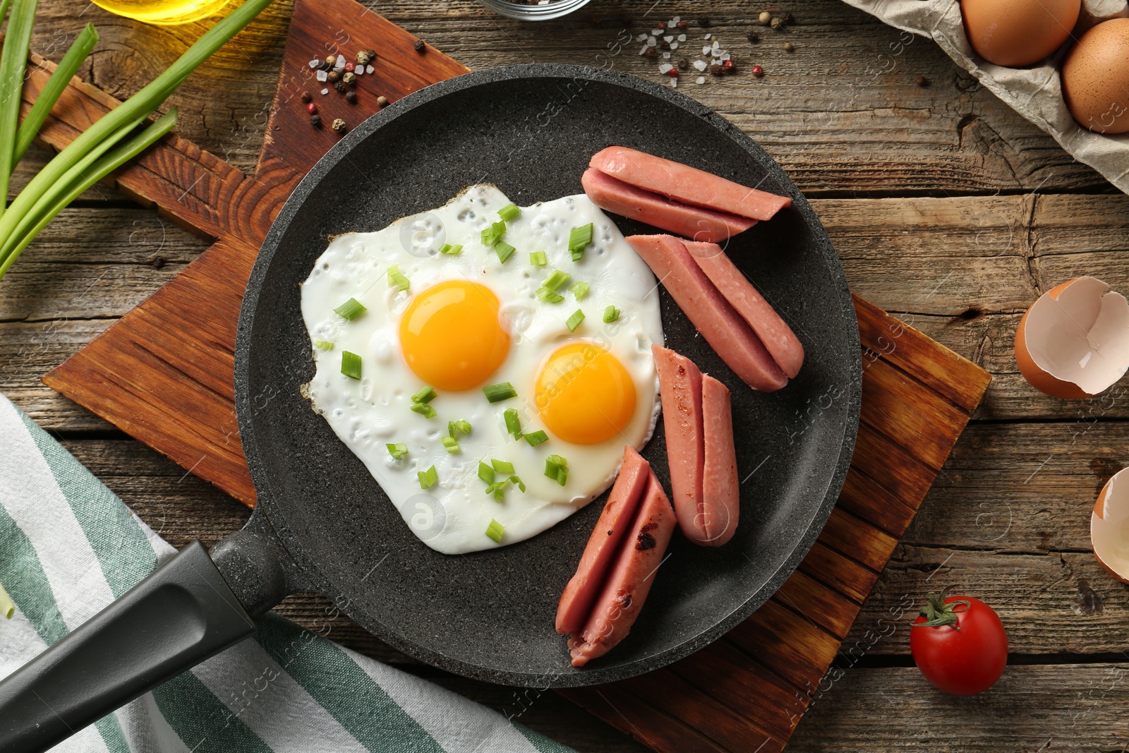 Photo of Tasty fried eggs with cut sausages served on wooden table, flat lay