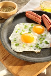 Photo of Tasty fried eggs with cut sausages served on table, closeup