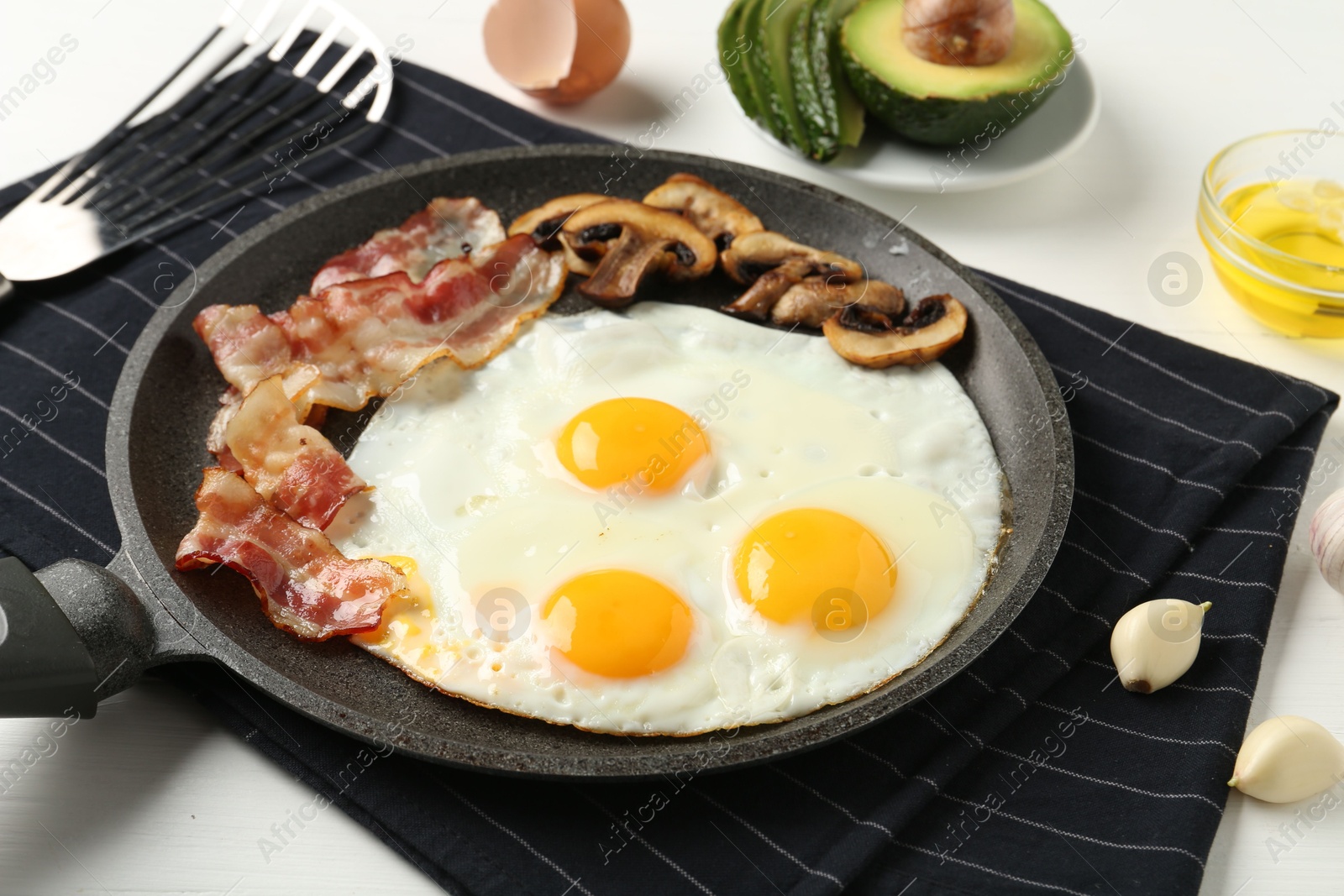 Photo of Tasty fried eggs with bacon and mushrooms served on white table, closeup