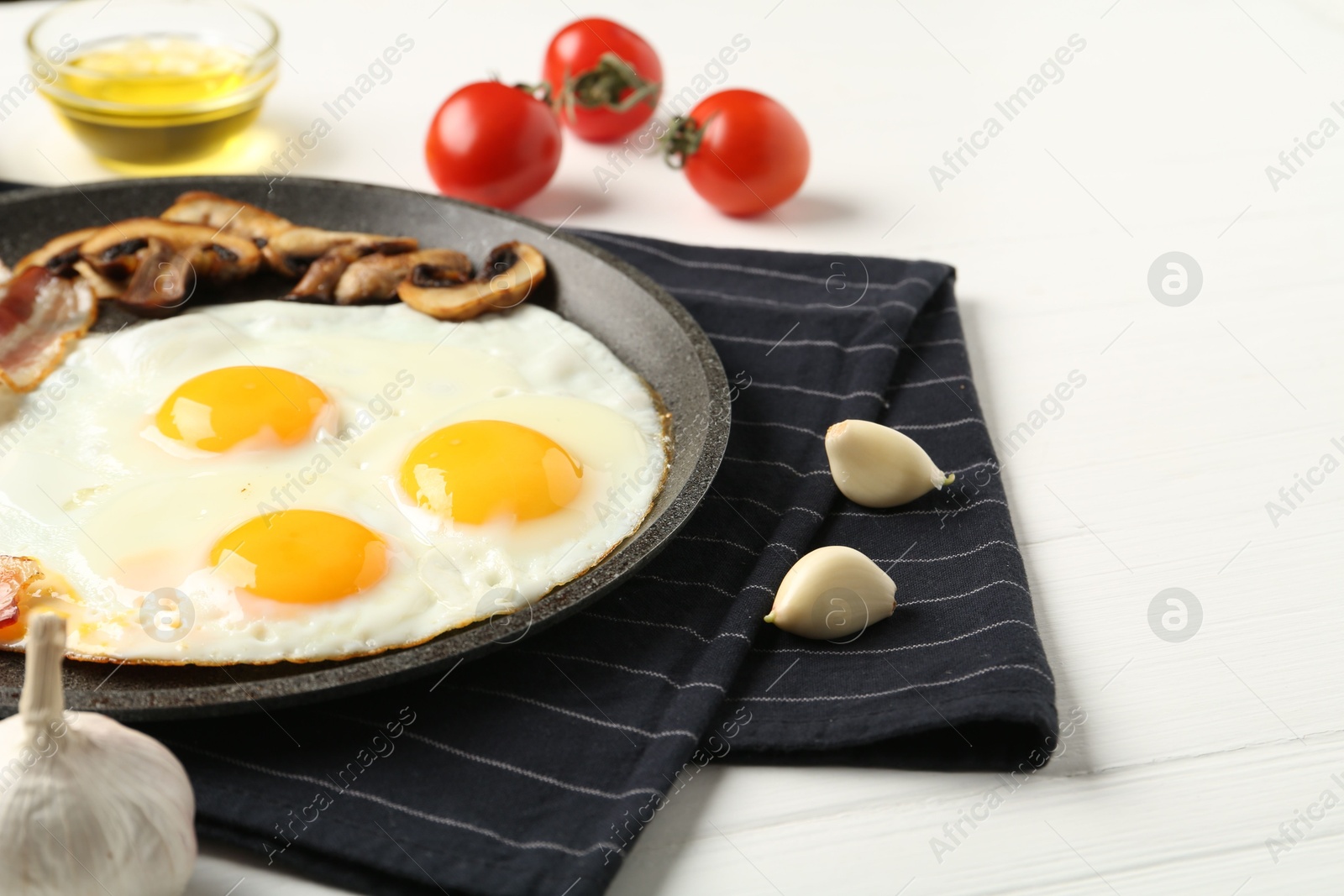 Photo of Tasty fried eggs with mushrooms served on white wooden table, closeup. Space for text