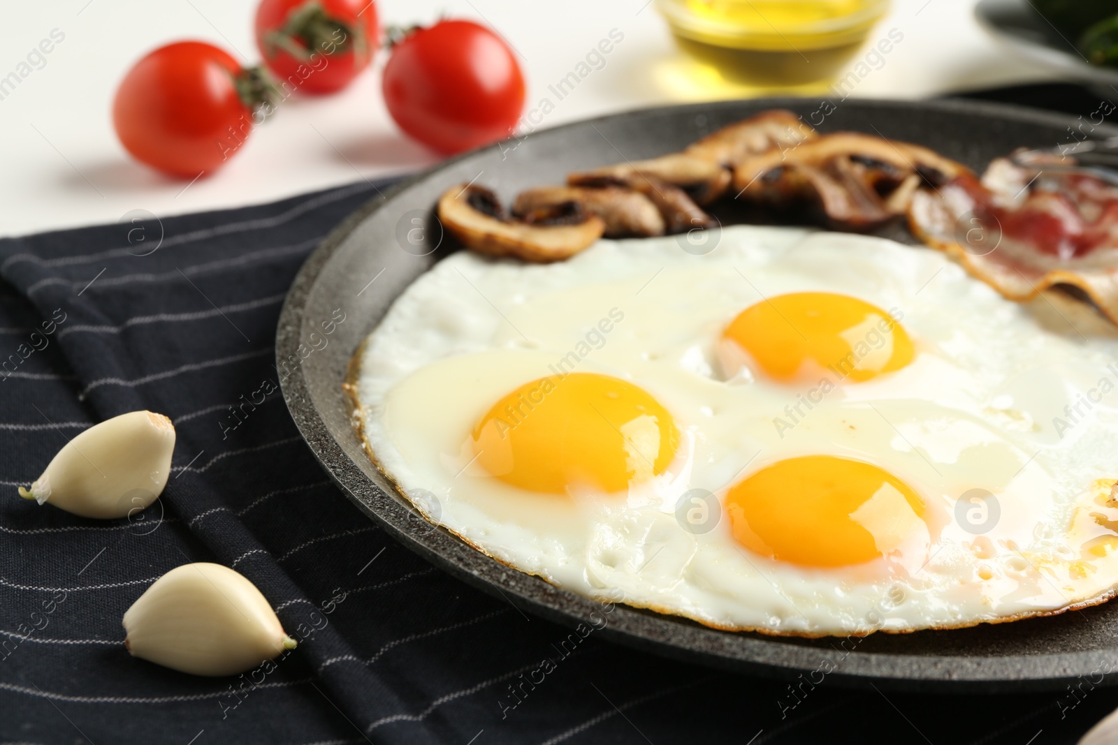 Photo of Tasty fried eggs with bacon and mushrooms served on table, closeup