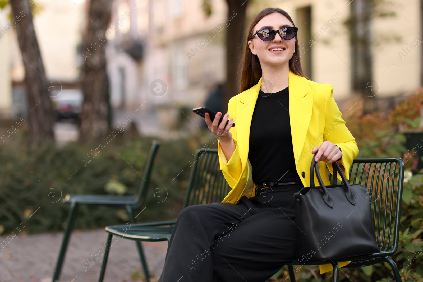 Photo of Smiling businesswoman in stylish suit with smartphone outdoors. Space for text