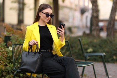 Photo of Businesswoman in stylish suit with smartphone outdoors. Space for text