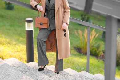 Photo of Businesswoman in stylish suit on stairs outdoors, closeup. Space for text