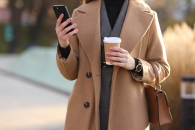 Photo of Businesswoman in stylish suit using smartphone outdoors, closeup