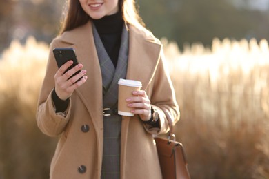 Photo of Smiling businesswoman in stylish suit using smartphone outdoors, closeup. Space for text