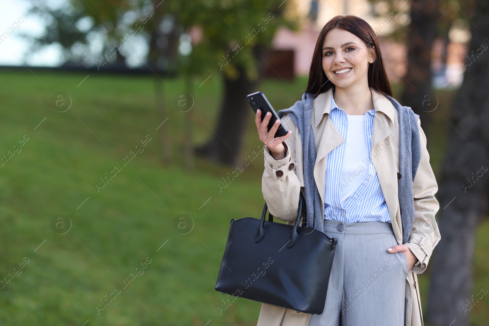 Photo of Smiling businesswoman in stylish suit with smartphone outdoors. Space for text