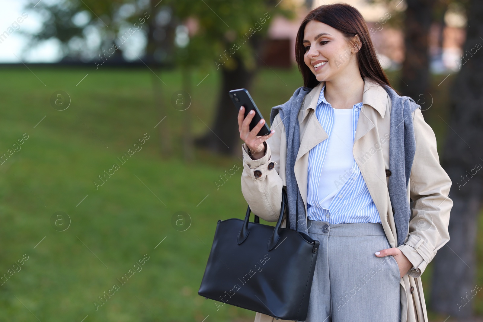 Photo of Smiling businesswoman in stylish suit with smartphone outdoors. Space for text