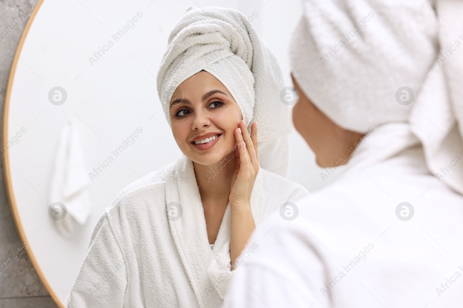 Photo of Washing face. Happy woman looking at mirror in bathroom