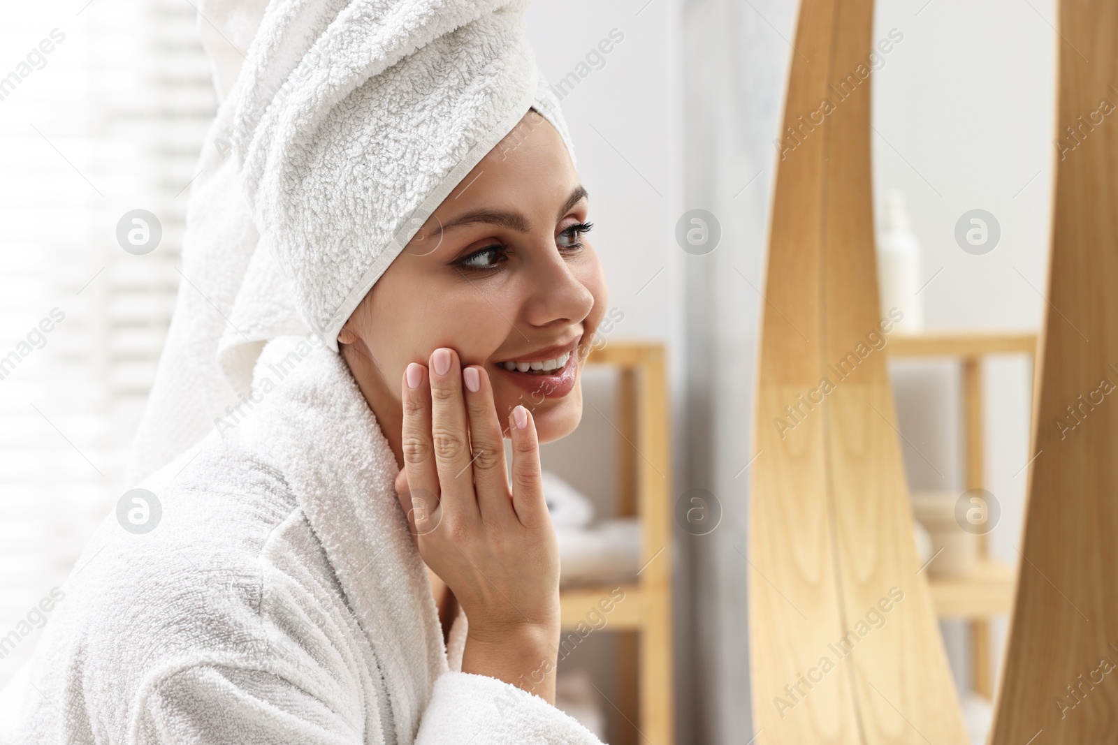 Photo of Washing face. Happy woman looking at mirror in bathroom