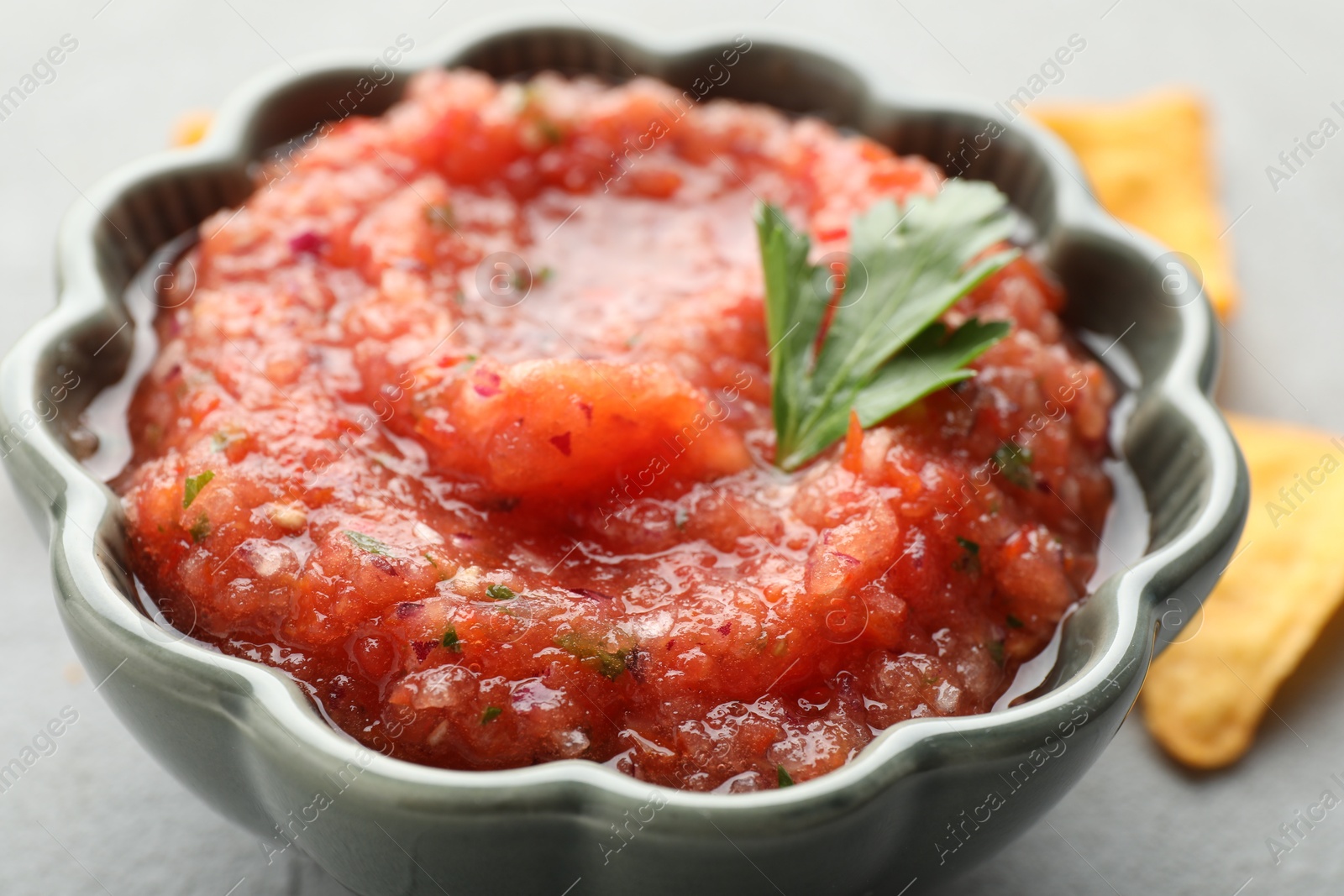 Photo of Delicious spicy salsa sauce in bowl on grey table, closeup