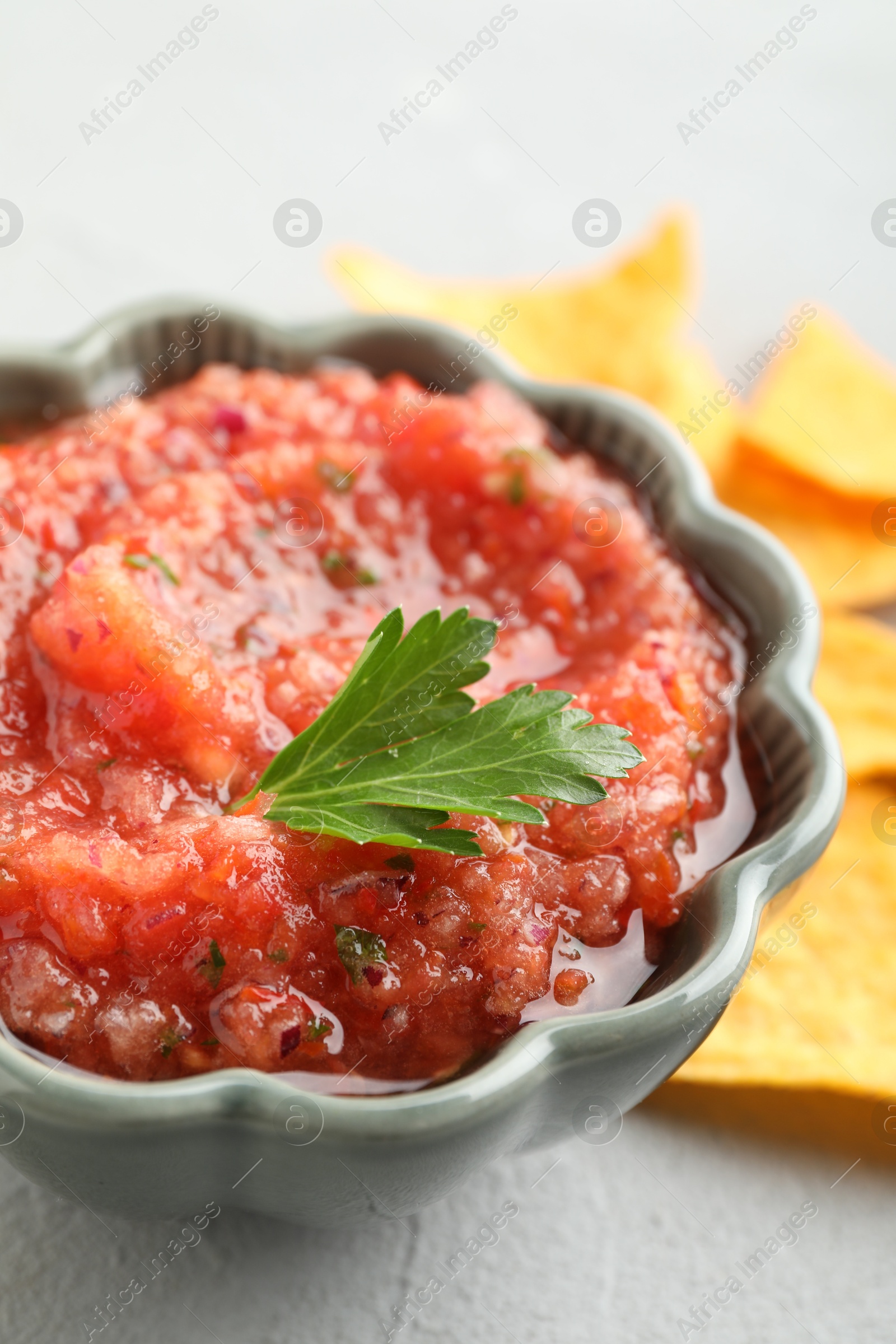 Photo of Delicious spicy salsa sauce in bowl on grey textured table, closeup