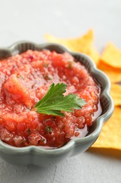 Photo of Delicious spicy salsa sauce in bowl on grey textured table, closeup